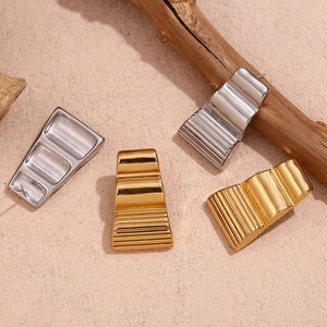 Macro detail of trapezoid geometric earrings with 18K gold and silver textured stripes