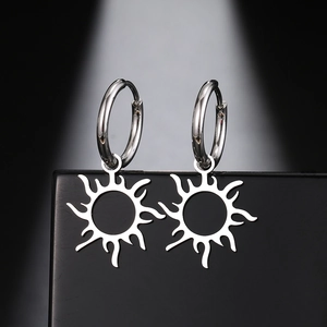 Vue détaillée de boucles d'oreilles créoles avec pendentif soleil argenté poli sur socle