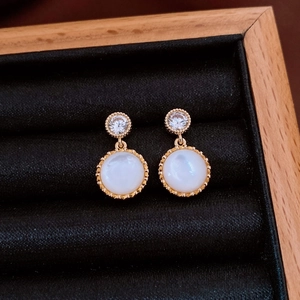 Macro detail of vintage gold resin earrings with zircon stones on black velvet display
