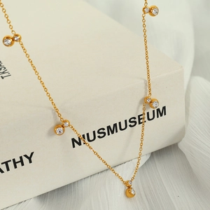 Elegant gold chain necklace with zircon pendants displayed on a classic book