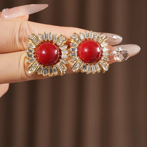 Close-up of vintage square gold earrings with a red center bead and clear zircon stones