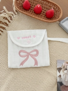Close-up of white quilted pouch with pink bow embroidery and a sweet lettering detail