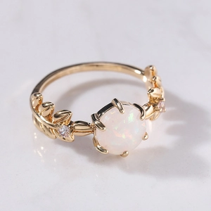 Dettaglio macro di un anello dorato a foglia con opale bianco e zirconi lucidi
