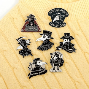 Detailed close-up of 7 plague doctor enamel pins on a cozy beige knitted sweater