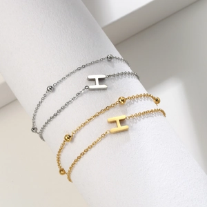 Close-up of double layer stainless steel chain bracelet with H letter charm in gold and silver