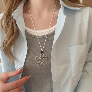 Minimalist silver flower pendant necklace with white cord chain worn by a female model