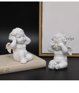 Detail van witte hars engelbeeldjes met vleugels in hoort-geen-kwaad en ziet-geen-kwaad poses