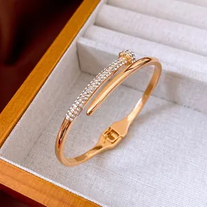 Luxury gold nail-shaped open bangle with sparkling pave diamond accents in a jewelry box