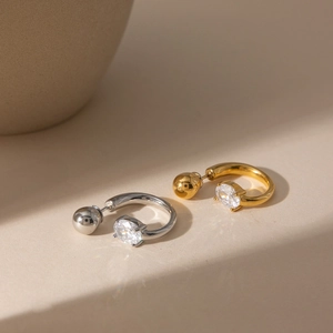 Détail macro des boucles d'oreilles C en or 18 carats et argent avec zircons ovales