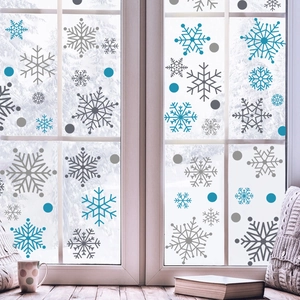 Winter snowflake window stickers in blue and grey hues on glass with snowy forest background