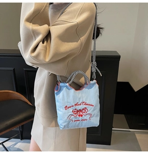 Close-up of light blue canvas bag with red bow and cherry embroidery detailing