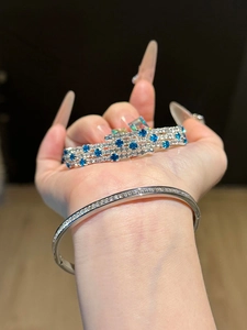 Detailed view of silver three-layer bracelet with blue and white zircon stones on hand
