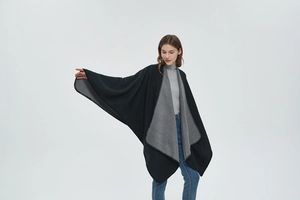 Detail of double-sided knit poncho showing elegant drape and decorative edge stitching