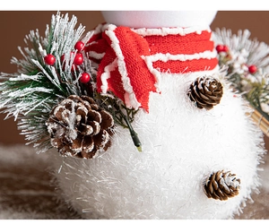 Macro detail of plush white snowman with LED lights, red scarf, pine cones and berries