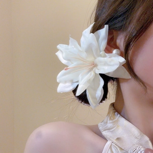 Detail of a large white fabric lily hair clip worn elegantly on the side of the head