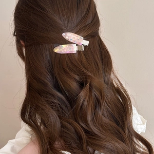 Detail of elegant water drop hair clips with rhinestones on brown curly hair