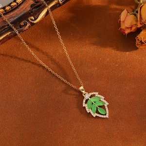 Elegant gold leaf necklace with green opal and diamonds on a warm vintage background