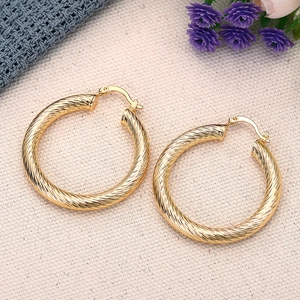Dettaglio macro di grandi orecchini a cerchio dorati con un design a trama a spirale