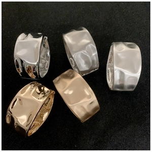 Detail of hammered metal wide rings with textured irregular liquid gold and silver finish