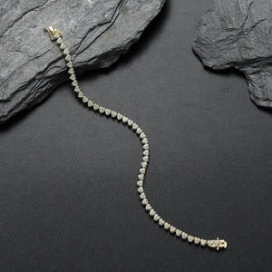 Macro view of golden heart tennis bracelet with micro-pave crystals on dark rock background