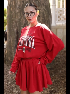 Foto outdoor di un set felpa rossa in maglia con stampa e gonna a pieghe