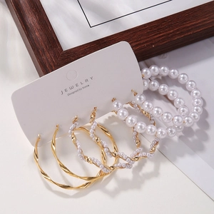 Detailansicht eines 3-teiligen Ohrring-Sets mit goldenen Creolen und weißen Perlenringen