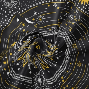 Macro detail of sun and star patterns on black fabric with gold and white accents