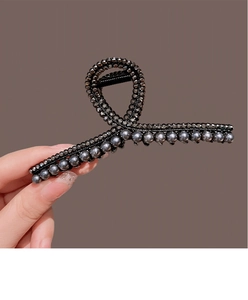 Detail of a curved black metal claw clip with grey pearls and sparkling crystals