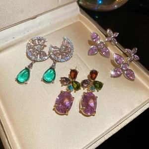 Macro shot of colorful gemstone drop earrings featuring zircon studs in a luxury jewelry box