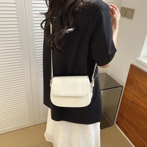 Minimalist white leather saddle bag for women with cross-body strap shown on a model