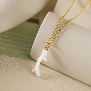 Détail d'un collier doré avec pendentif bois de cerf blanc en forme de corail sur support