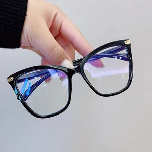 Detail of black cat-eye eyeglass frames with gold accents and anti-blue light lenses