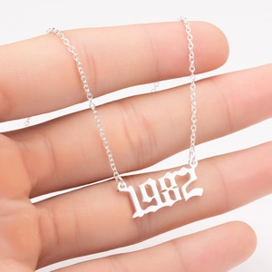 Macro shot of a personalized 1982 gothic number pendant necklace held by a hand