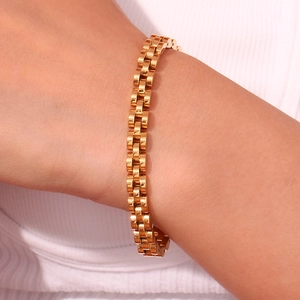 Detail of 18K gold-plated stainless steel watch-strap style bracelet on wrist