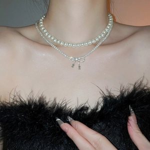 Detail of layered pearl necklace with zircon bow pendant on model neck