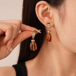Vintage irregular amber acrylic earrings with golden metal studs shown on a model