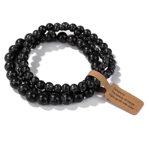 Detail of 4mm-8mm black stone bead bracelets with natural white texture and paper tag