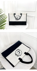 Close-up of large canvas tote bag with black contrast trim and floral 'C' monogram