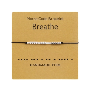Detail of silver beads on black cord Morse Code bracelet with Breathe card packaging