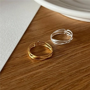 Detailed close-up of overlapping gold and silver minimalist rings on a wood texture
