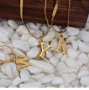 Detailed macro of 18K gold plated snake bone necklaces with initial M Y K pendants