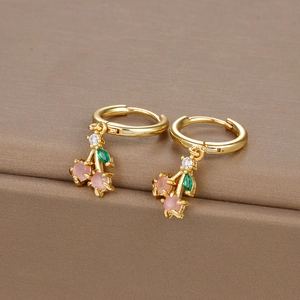 Close-up of gold cherry earrings with pink matte beads and green zircon leaves