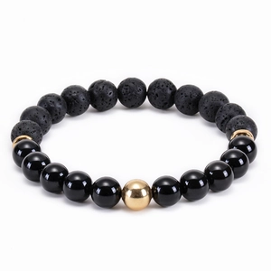 Macro detail of elastic beaded bracelet with black lava stone and gold metallic accents