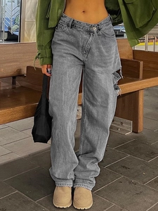 Jeans ampi grigi da donna con vita asimmetrica e dettaglio cut-out su panca di legno
