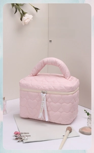 Close-up of pink heart quilted makeup bag with white love ribbon and dual zipper detail