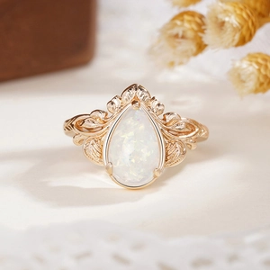 Macro shot of pear-cut opal ring with vintage rose gold lace filigree details