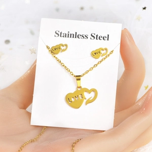 Close-up of golden stainless steel heart jewelry set with LOVE engraving and card