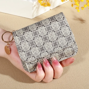 Detail of a foldable women's wallet with grey geometric pattern and gold keychain