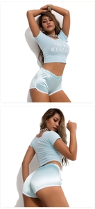 Detail of light blue crop top with text and matching glossy athletic shorts set
