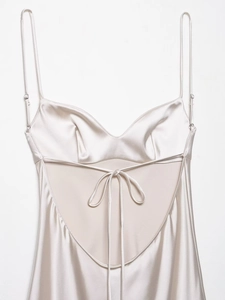 Detailed view of champagne satin dress featuring cross-back tie straps and silky texture